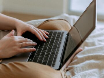 faceless woman using laptop while sitting on bed