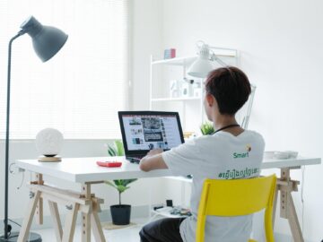 young man in white shirt sitting on chair using laptop