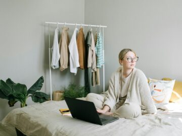 a woman in beige sweater sitting on the bed